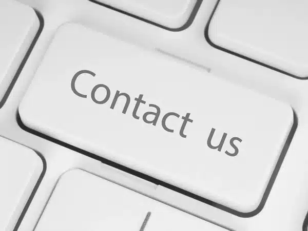 Close-up of a white computer keyboard focusing on a key that reads “Contact us” in a clean, minimalist style.